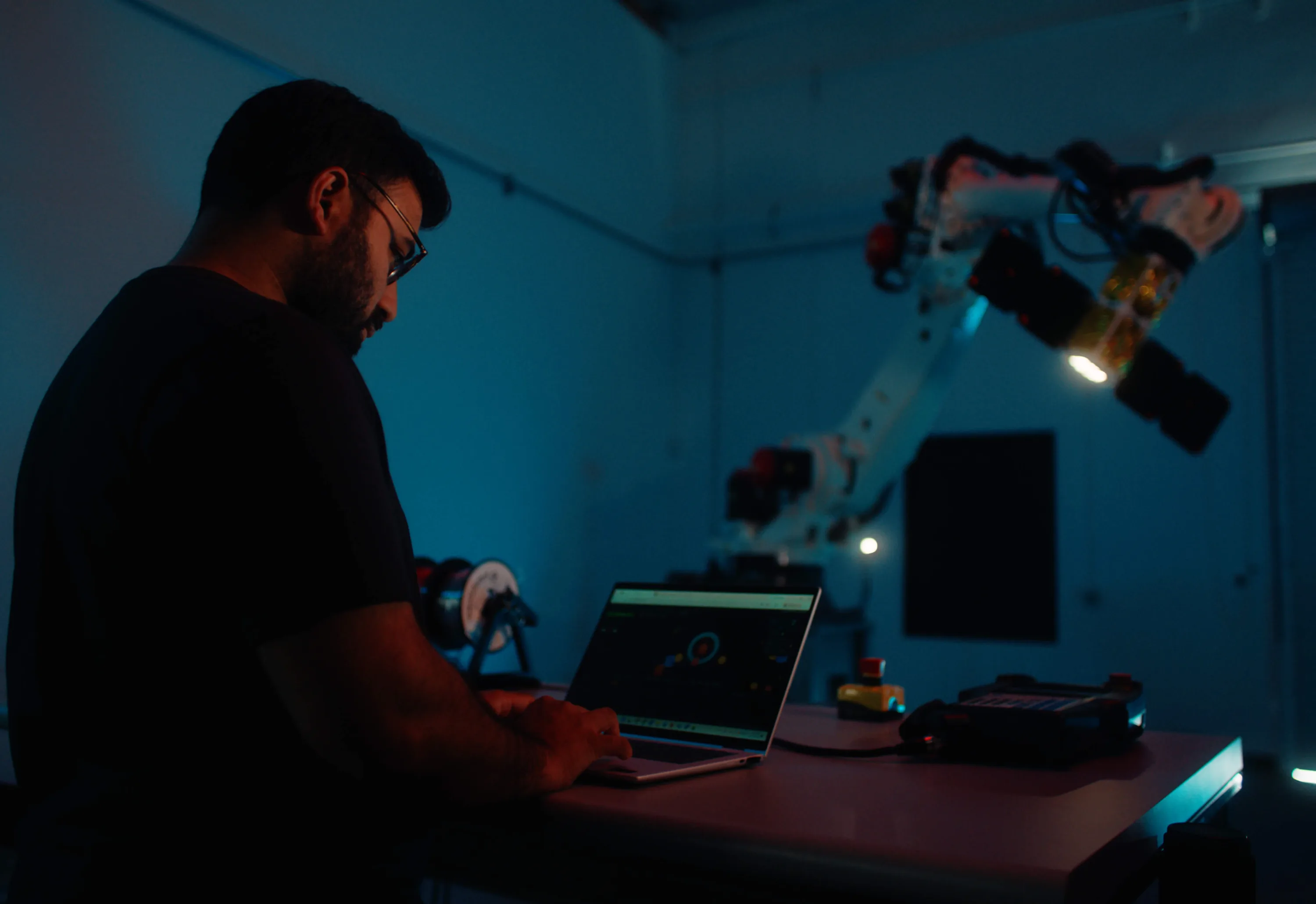 A Fortastra engineer working at a test station beside the robotic spacecraft rig