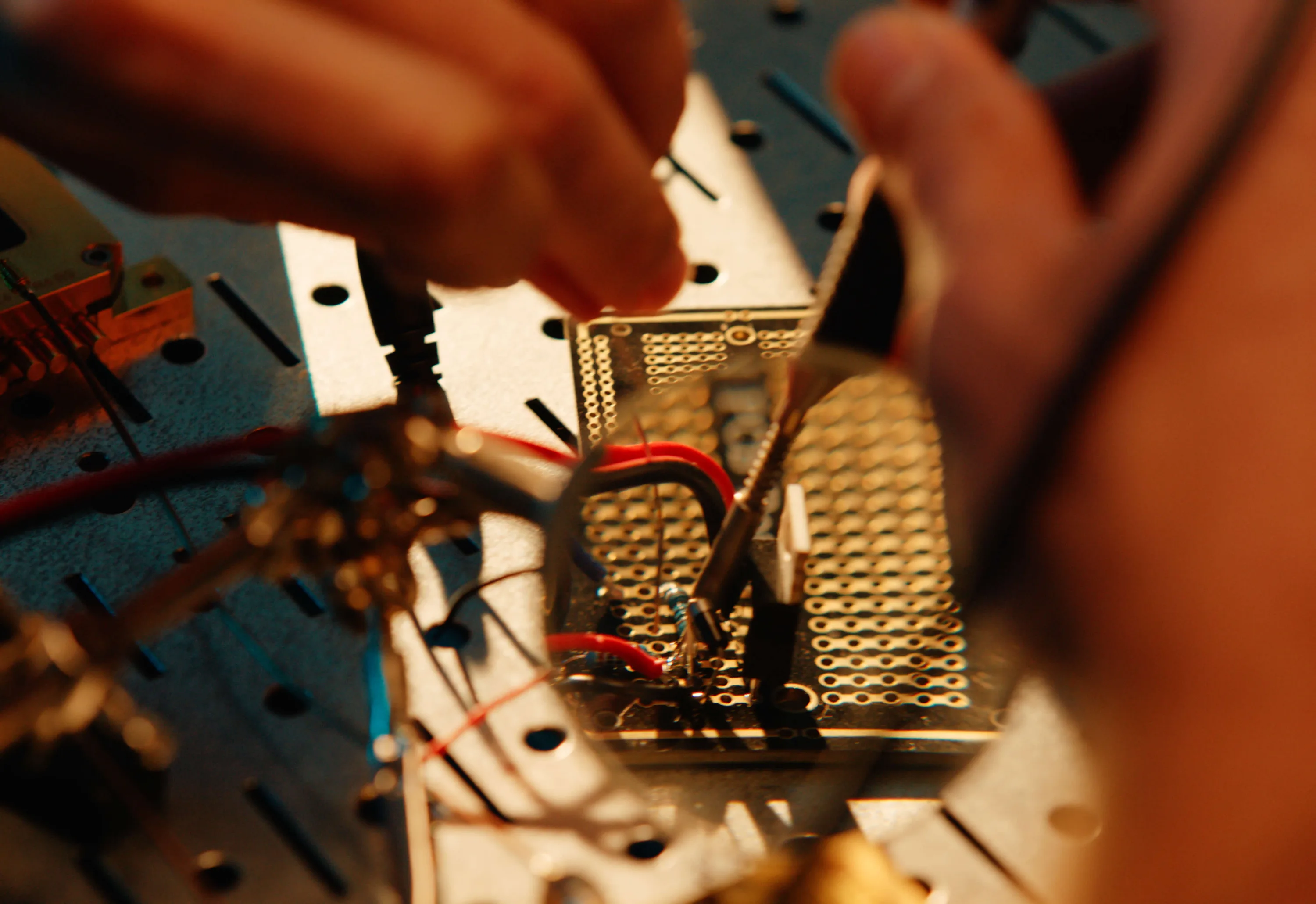 Hands assembling spacecraft electronics as light catches the hardware